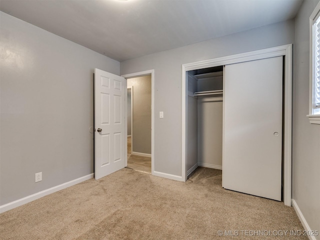 unfurnished bedroom featuring a closet, baseboards, and carpet floors