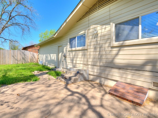 view of home's exterior with a patio area and fence