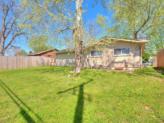 back of house featuring crawl space, fence, and a lawn