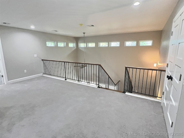 carpeted empty room featuring baseboards, visible vents, and recessed lighting