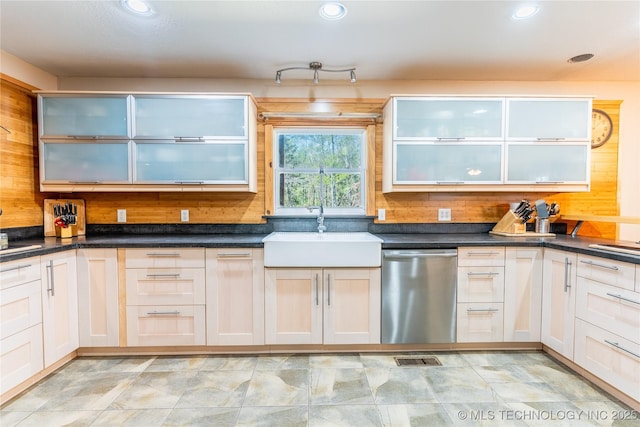 kitchen featuring stainless steel dishwasher, a sink, and dark countertops