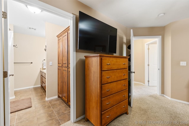 corridor featuring light tile patterned floors, visible vents, and baseboards