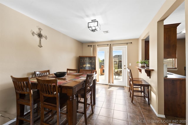 dining space featuring visible vents and dark tile patterned flooring