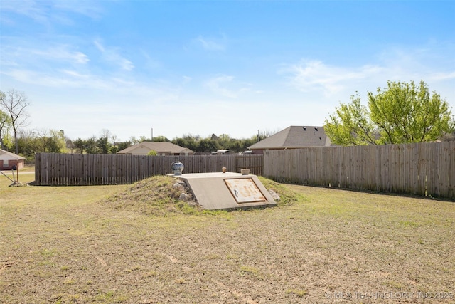 entry to storm shelter featuring a fenced backyard and a lawn