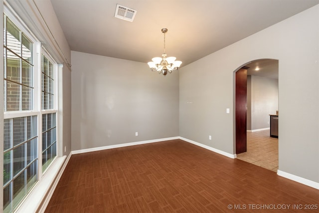 705 SW 20th St, Wagoner, OK 74467 - unfurnished room featuring arched walkways, visible vents, wood finished floors, baseboards, and a notable chandelier