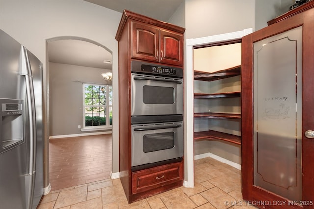 705 SW 20th St, Wagoner, OK 74467 - kitchen featuring baseboards, arched walkways, an inviting chandelier, and stainless steel appliances