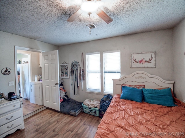22526 N 2860th Rd, Kingfisher, OK 73750 - bedroom featuring washer / clothes dryer, a textured ceiling, visible vents, ceiling fan, and wood finished floors