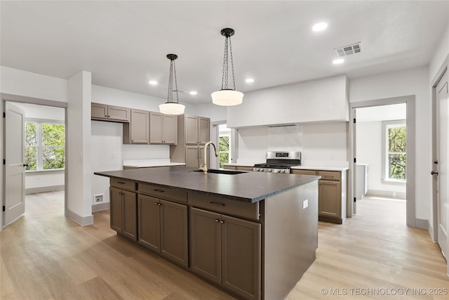 824 Wilson, Durant, OK 74701 - kitchen featuring visible vents, a sink, light wood-type flooring, dark countertops, and stainless steel gas stove