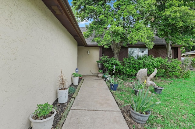 6370 S 29th W Pl, Tulsa, OK 74132 - view of exterior entry with stucco siding, a shingled roof, and a yard