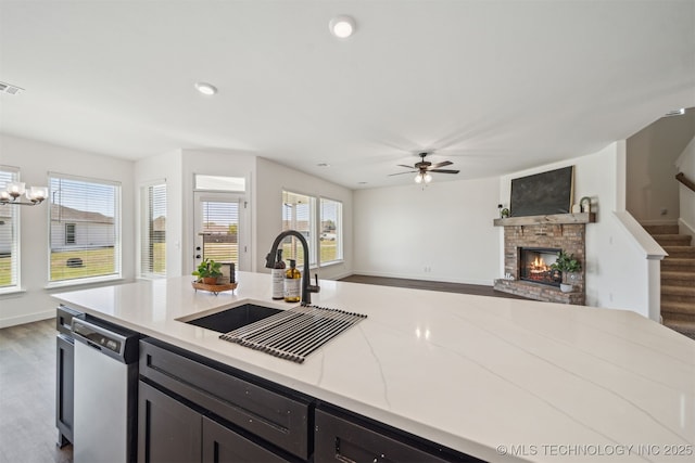 kitchen with ceiling fan, wood finished floors, dishwasher, a sink, and open floor plan