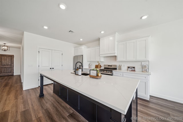 kitchen featuring dark wood finished floors, a large island with sink, white cabinets, appliances with stainless steel finishes, and a sink