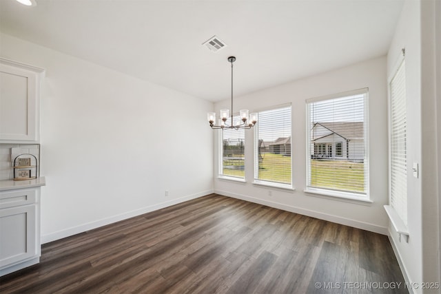unfurnished dining area featuring baseboards, a notable chandelier, dark wood-style floors, and visible vents