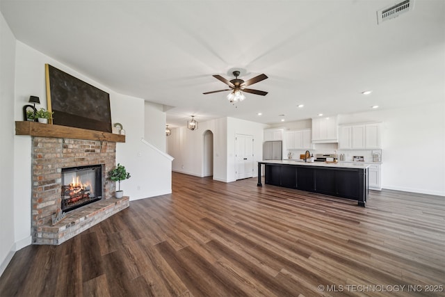 unfurnished living room with visible vents, baseboards, ceiling fan, and dark wood-style floors