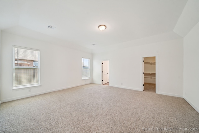 unfurnished bedroom featuring a walk in closet, baseboards, carpet, and visible vents