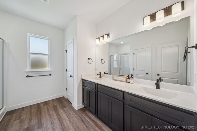 full bathroom featuring a stall shower, wood finished floors, double vanity, and a sink