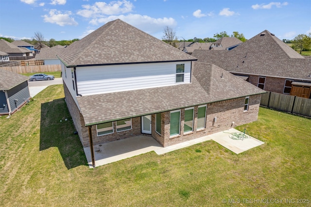 rear view of house featuring a patio area, brick siding, a yard, and a shingled roof
