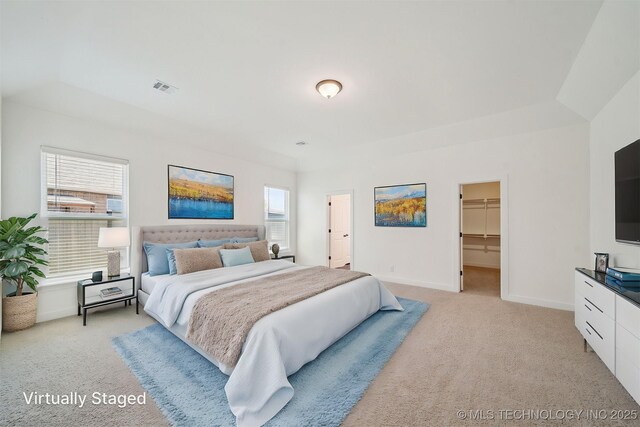 bedroom with a closet, baseboards, a walk in closet, visible vents, and light colored carpet
