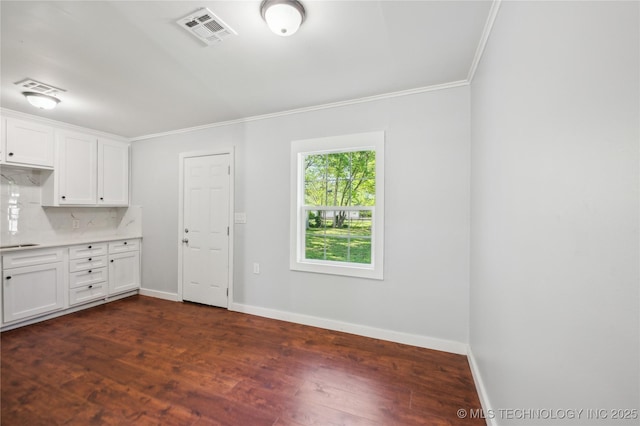 920 E 33rd St N, Tulsa, OK 74106 - kitchen with crown molding, white cabinets, baseboards, light countertops, and dark wood-type flooring