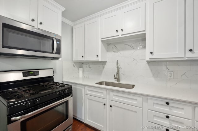 920 E 33rd St N, Tulsa, OK 74106 - kitchen with stainless steel appliances, a sink, white cabinetry, backsplash, and ornamental molding