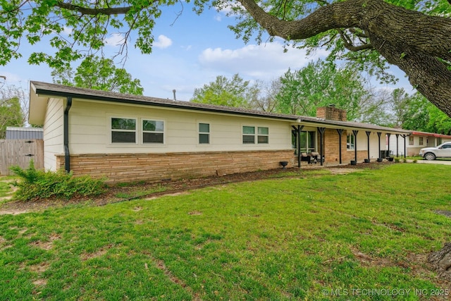 ranch-style home featuring fence, a front lawn, a chimney, and stone siding