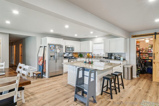 kitchen featuring a breakfast bar, light wood-type flooring, a kitchen island, and appliances with stainless steel finishes