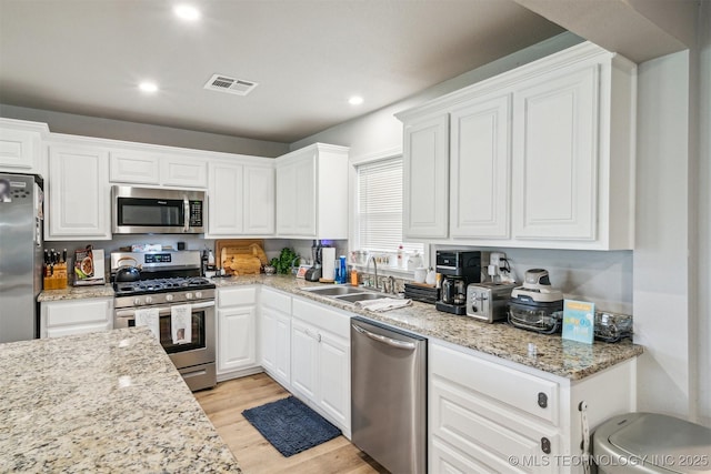 kitchen featuring light wood finished floors, a sink, visible vents, white cabinetry, and appliances with stainless steel finishes