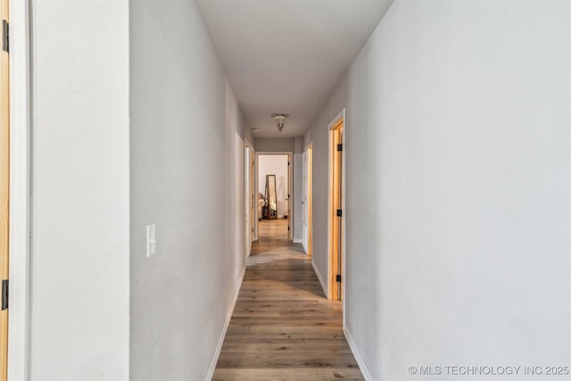 corridor with baseboards and wood finished floors