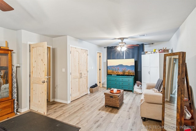 living area featuring visible vents, baseboards, wood finished floors, and ceiling fan