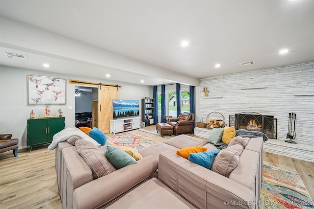 living room featuring a barn door, light wood-style flooring, visible vents, and recessed lighting