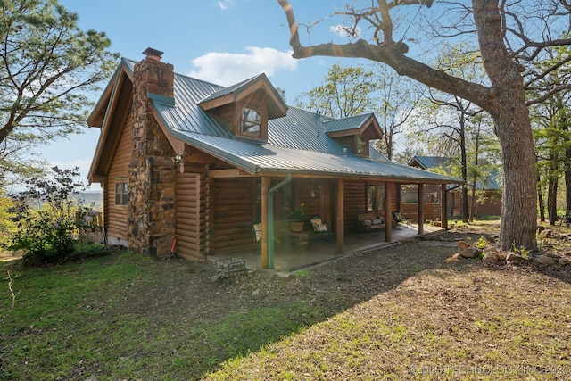 14484 Valley View Dr, Skiatook, OK 74070 - rear view of property featuring log exterior, a metal roof, a chimney, and a patio area