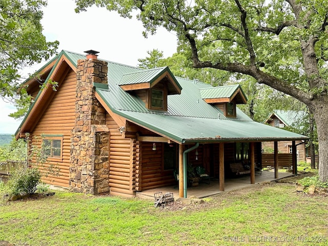 14484 Valley View Dr, Skiatook, OK 74070 - back of house featuring a chimney, a yard, log siding, and a metal roof