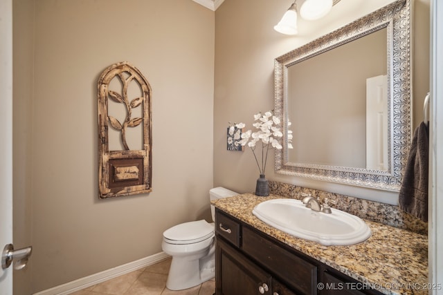 bathroom with baseboards, toilet, crown molding, vanity, and tile patterned floors
