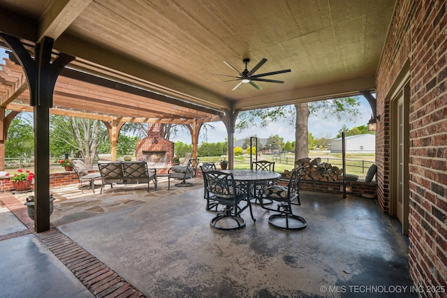 view of patio featuring an outdoor brick fireplace, outdoor dining space, ceiling fan, and fence