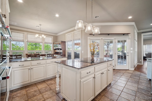 kitchen featuring black electric stovetop, a chandelier, a center island, white cabinetry, and visible vents