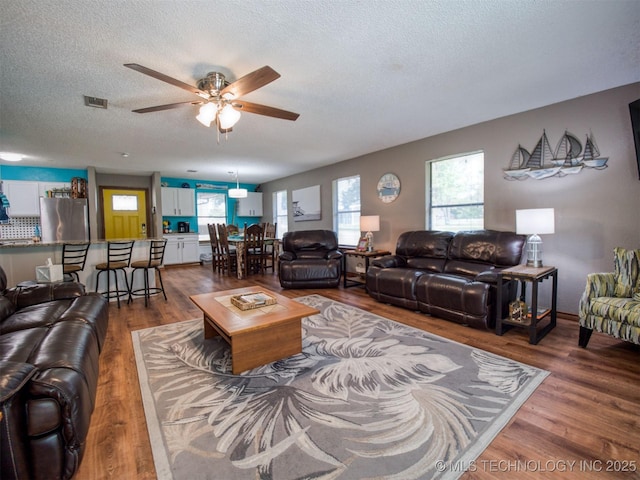 1668 Waters Rd, Kingston, OK 73439 - living area featuring dark wood-style flooring, visible vents, a ceiling fan, and a textured ceiling