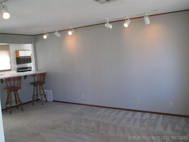 carpeted dining area featuring rail lighting and baseboards
