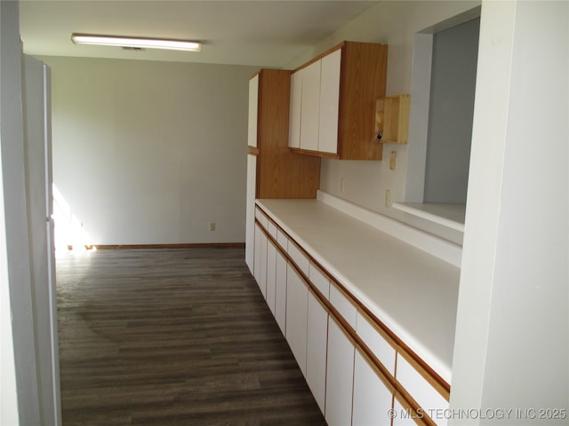 kitchen featuring white cabinetry, dark wood finished floors, light countertops, and baseboards