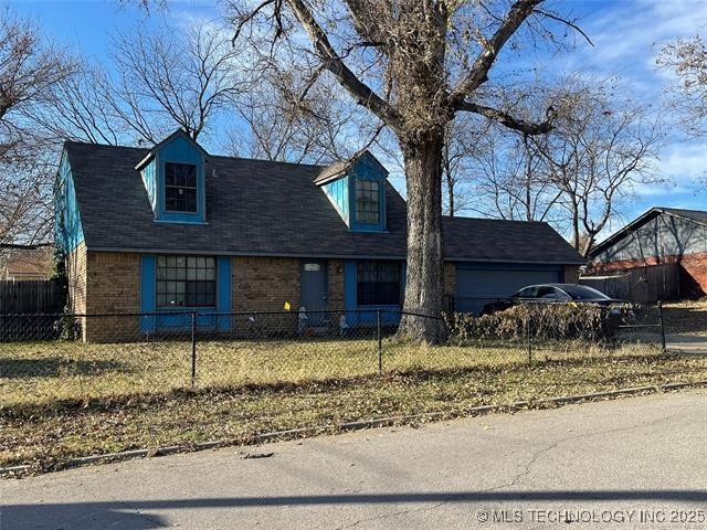 1204 N Detroit Ave, Tulsa, OK 74106 - cape cod home with brick siding and a fenced front yard