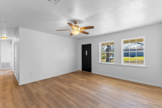 spare room with a textured ceiling, wood finished floors, and visible vents