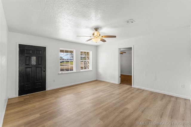 interior space featuring light wood finished floors, baseboards, a ceiling fan, and visible vents