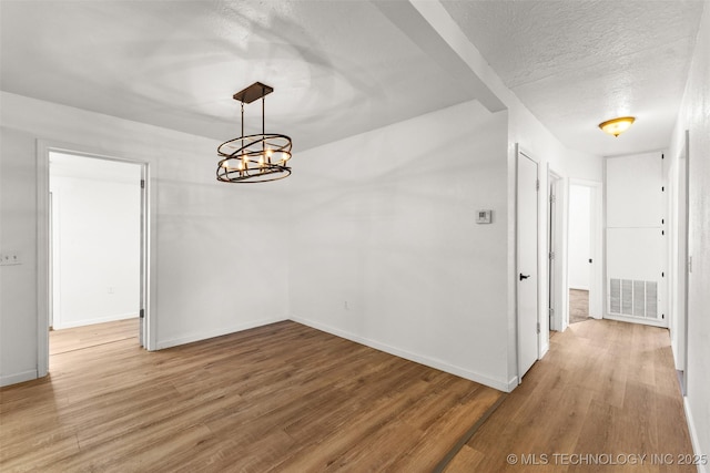unfurnished dining area featuring a chandelier, light wood-type flooring, and baseboards