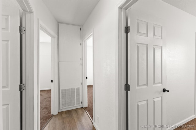 corridor with wood finished floors, baseboards, and visible vents