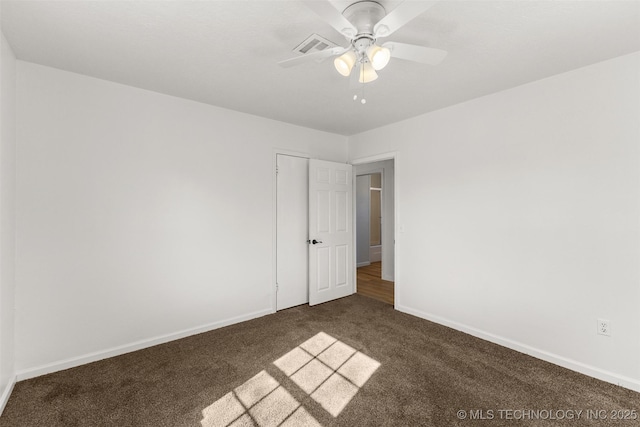 empty room featuring dark colored carpet, visible vents, baseboards, and ceiling fan