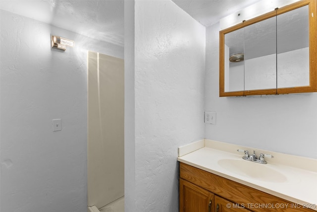 bathroom with a textured wall and vanity