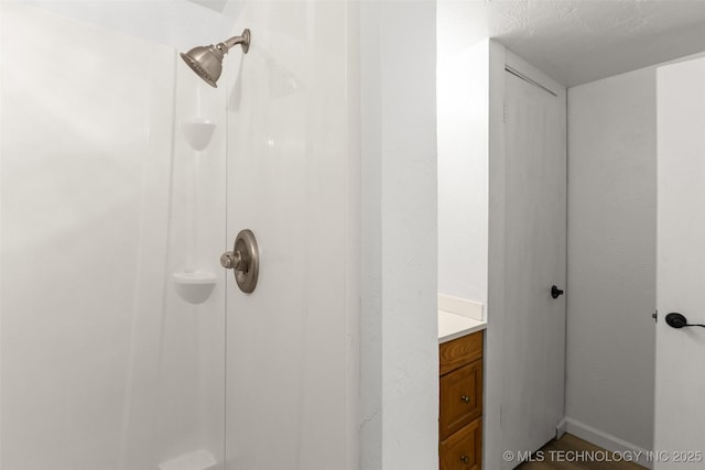 bathroom with vanity, baseboards, and walk in shower