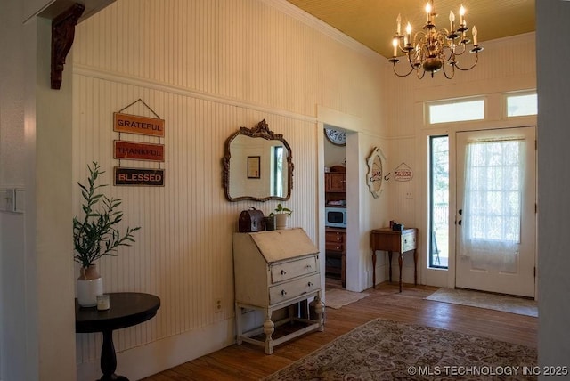foyer featuring a wealth of natural light, wood finished floors, a notable chandelier, and a towering ceiling