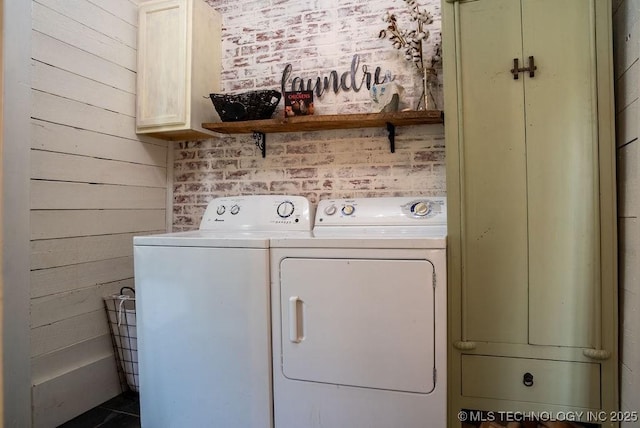 laundry area featuring wood walls, washing machine and dryer, and cabinet space