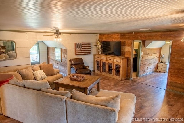 living room with wooden walls, a ceiling fan, and wood finished floors