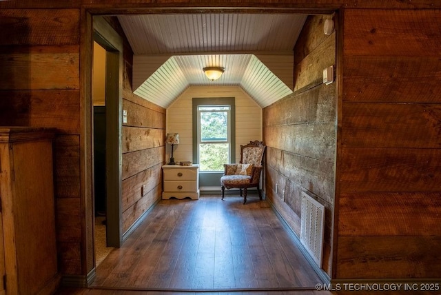 living area with vaulted ceiling, visible vents, hardwood / wood-style floors, wooden ceiling, and wood walls