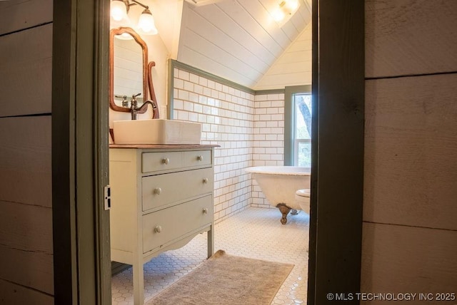 bathroom with vanity, vaulted ceiling, and tile walls